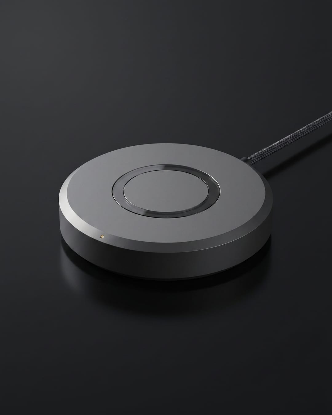 Studio packshot of the Driftlight rig — graphite aluminum puck with smoked-glass aperture ring